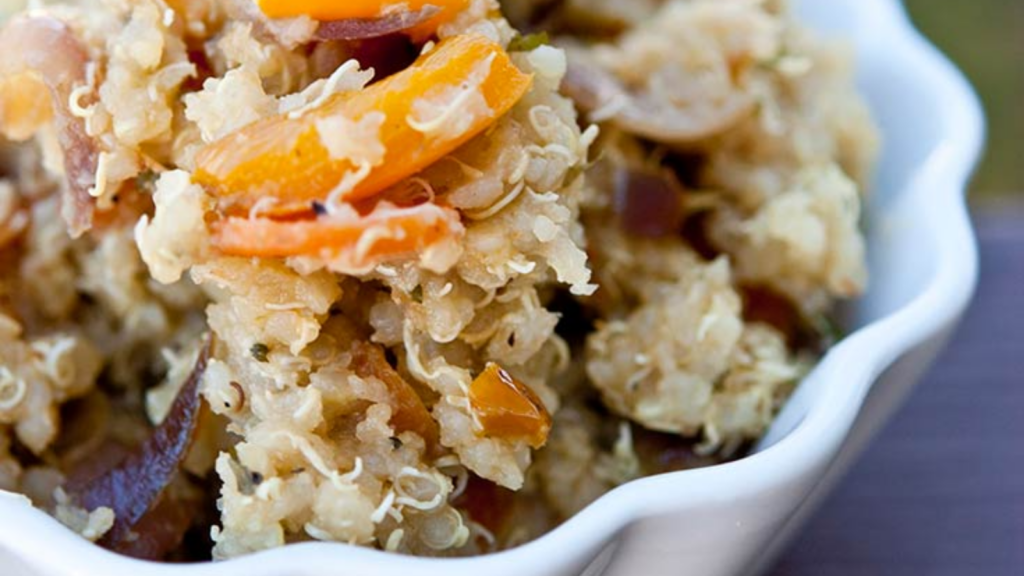 A micro closeup of a white, fluted bowl filled with vegetable quinoa.