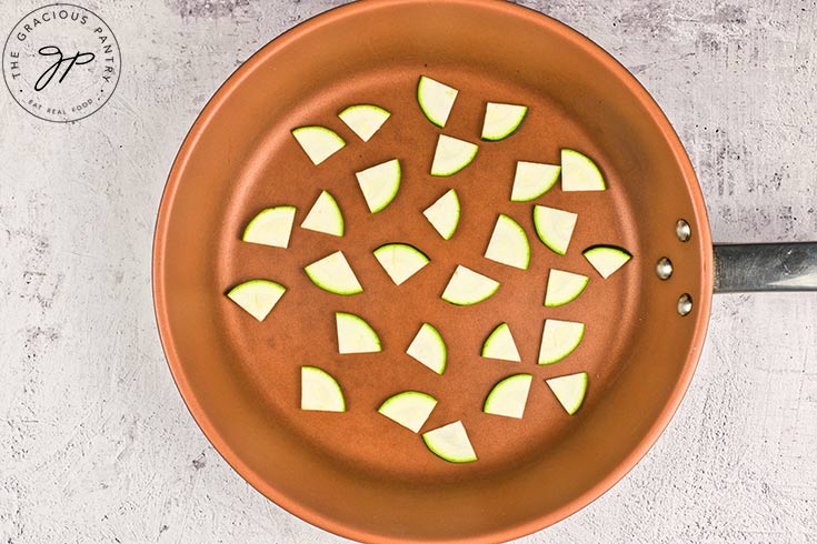 Raw zucchini pieces in a skillet.