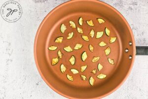 Zucchini pieces browned in a skillet.