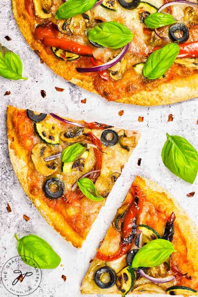 A closeup of veggie pizza slices on a white background.