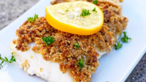 A cod fillet coated in ground walnuts and topped with a lemon slice.