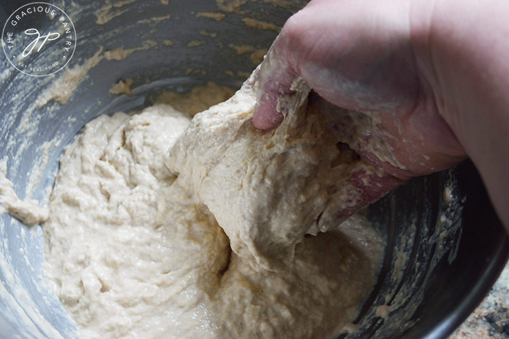 Showing the proper consistency of a wetter focaccia bread dough after adding more water.