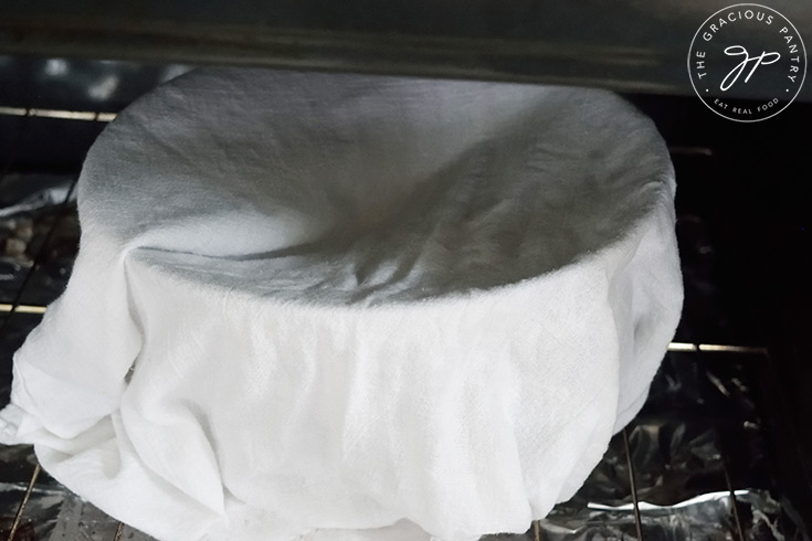 Setting the covered dough bowl in an unheated oven to rise.