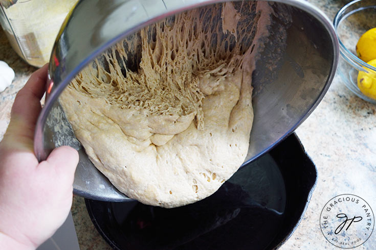 Pouring the dough from the mixing bowl into the greased skillet.