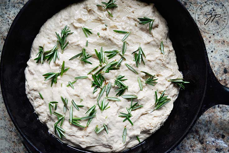 Fresh rosemary sprigs pressed into the raw focaccia dough.