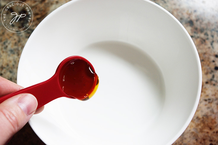 Putting honey in a medium mixing bowl.