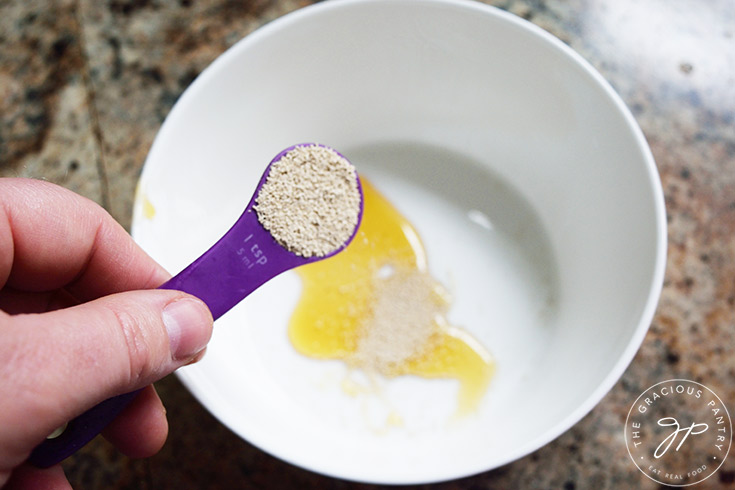 Adding yeast to honey in a medium mixing bowl.