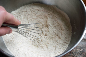Whisking salt and flour together in a mixing bowl.