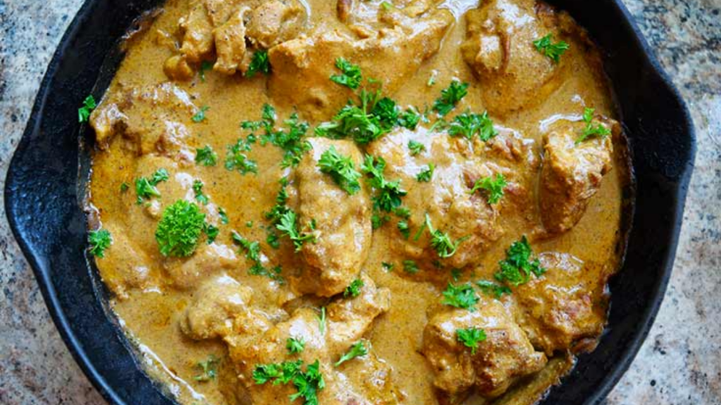 An overhead view of a cast iron skillet filled with yogurt chicken.