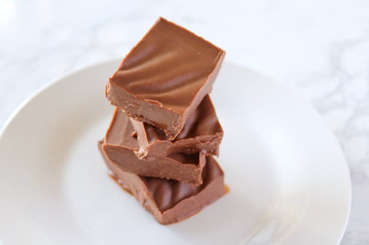 Four pieces of fudge stacked up on a white plate.