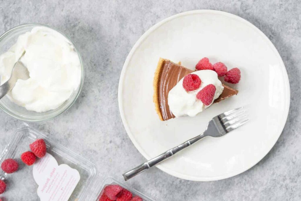 An overhead view of a slice of chocolate peanut butter pie on a white plate.