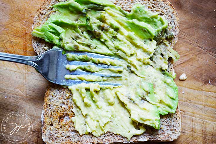 Smashing avocado on a slice of toast.