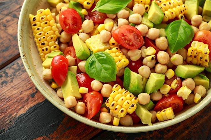 A bowl of cajun corn salad on a wood surface.