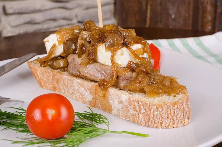 Caramelized onions garnishing a slice of bread with meat and cheese.
