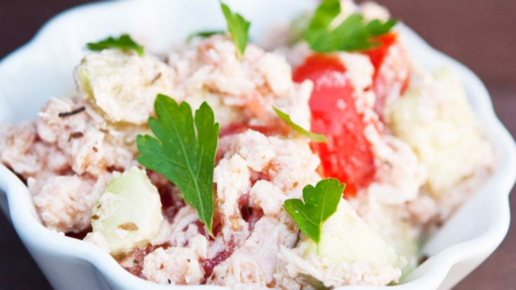 A white bowl filled with chicken cucumber salad.