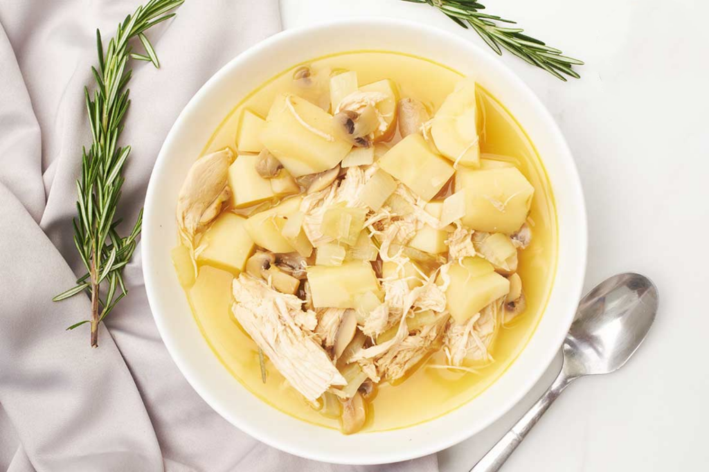 An overhead view of a white bowl filled with chicken parsnip soup.