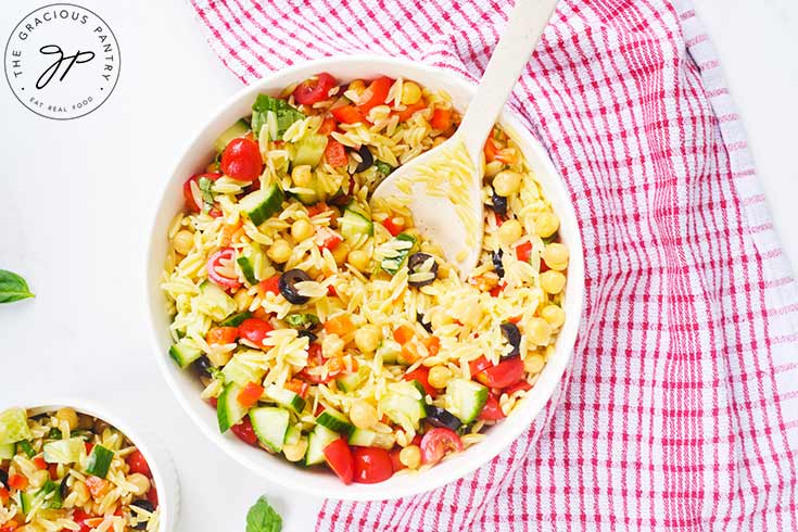 An overhead view of a white bowl filled with Chickpea Orzo Salad.