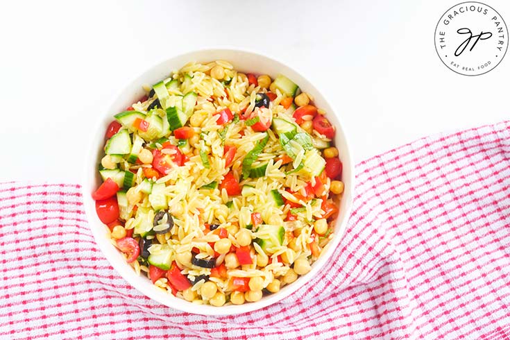 Chickpea Orzo Salad ingredients mixed together in a white mixing bowl.