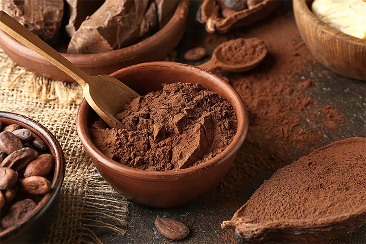A bowl of cocoa powder with a wooden scoop in it.