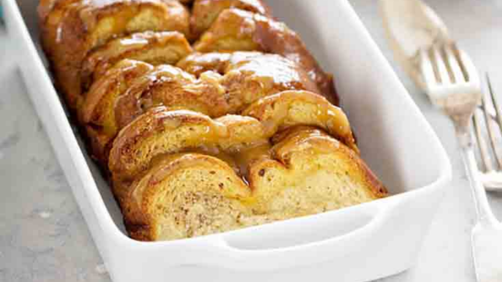 A white casserole dish filled with a row of french toast.