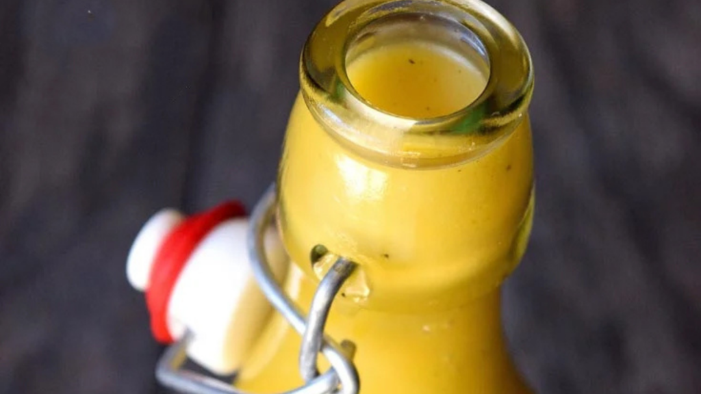The top of a glass bottle filled with garlic lemon vinaigrette.