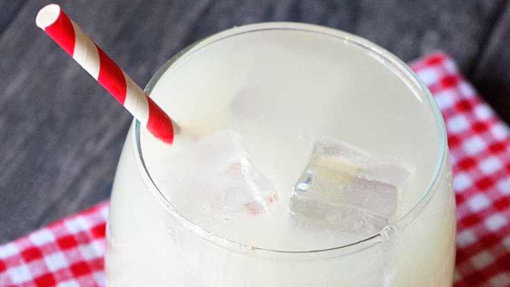 A glass of ginger ale with a red and white straw in it.