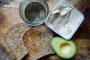 Hummus Avocado Toast Recipe ingredients gathered on a cutting board.