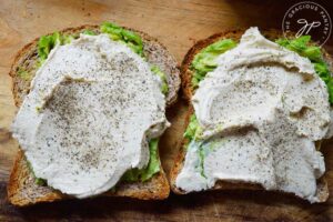 Pepper sprinkled over hummus on avocado toast.