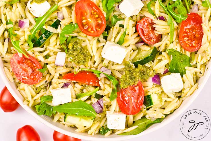 An overhead view of a white bowl filled with Orzo Salad With Pesto.
