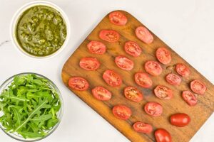 Grape tomatoes halved and laying on a cutting board.