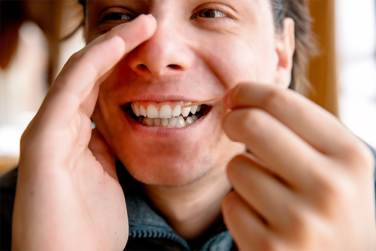 A man picking his teeth with a toothpick.