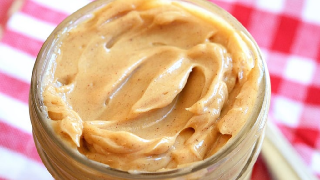 A closeup of an open jar filled with whipped pumpkin spice maple butter.