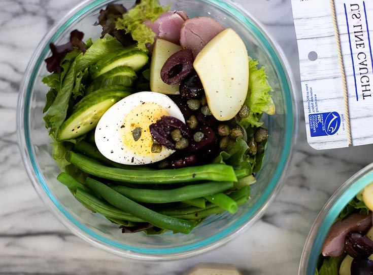 An overhead view of a glass bowl filled with tuna nicoise salad.