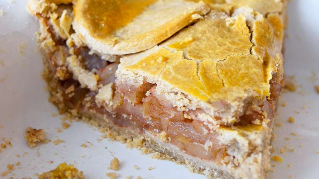 A closeup of a slice of apple pie in a white dish.