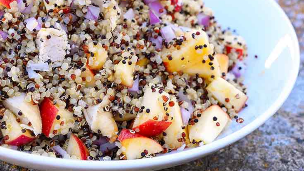 A white bowl filled with Chicken Quinoa Salad With Apples.
