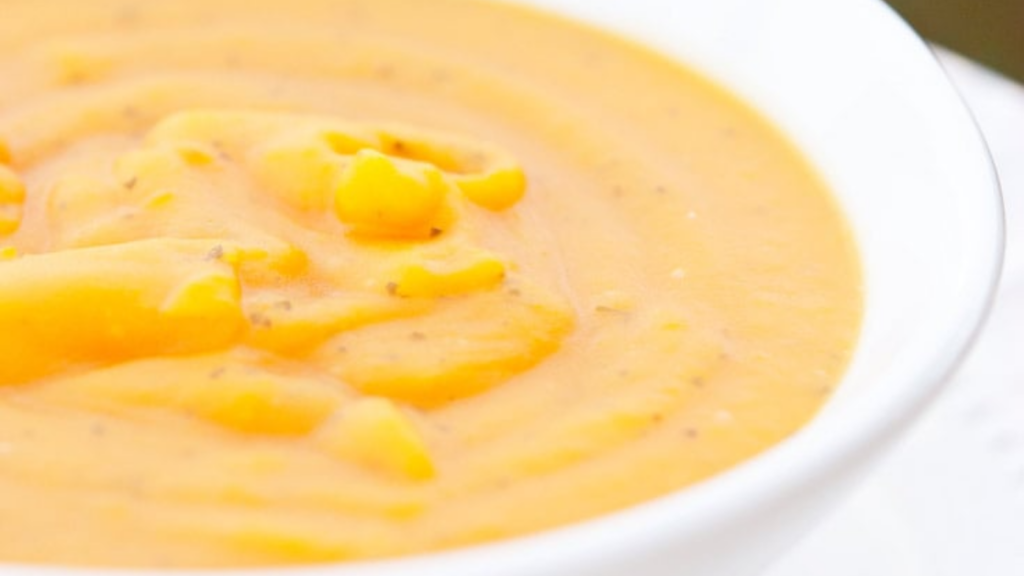 A closeup of a white bowl filled with butternut squash soup.
