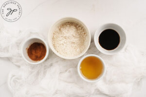 Honey glaze ingredients for Homemade Cinnamon Rolls in individual bowls on a white surface.