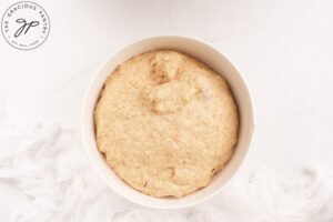 Homemade Cinnamon Rolls dough doubled in size after rising, in a white bowl.