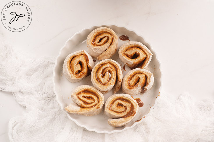 Rolled up and cut cinnamon rolls in a white, round baking dish.
