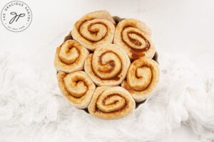 Risen cinnamon rolls in a white round baking dish.