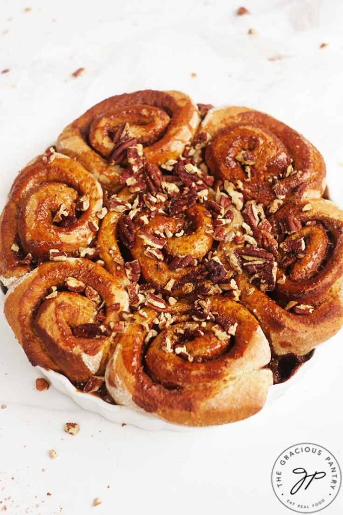 Baked cinnamon rolls topped with chopped pecans and honey glaze.