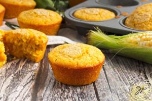 Baked cornbread muffins laying on a wood table.