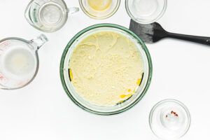 Wet cornbread muffin ingredients in a glass mixing bowl.