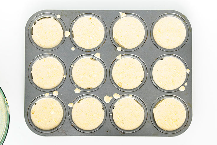 Batter poured into muffin liners in a muffin pan.