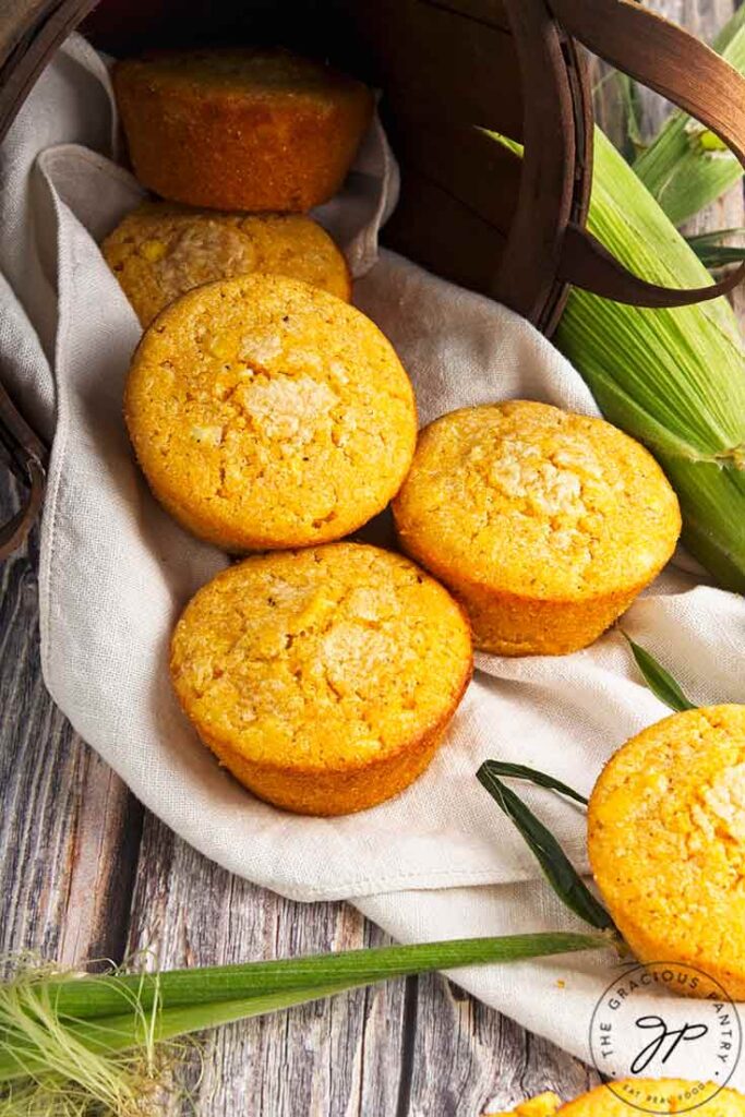 Several cornbread muffins laying on a towel on a wood table.