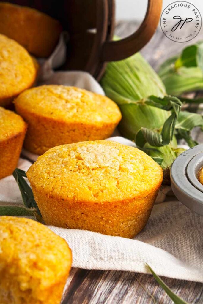 A closeup of cornbread muffins on a towel on a wood table.