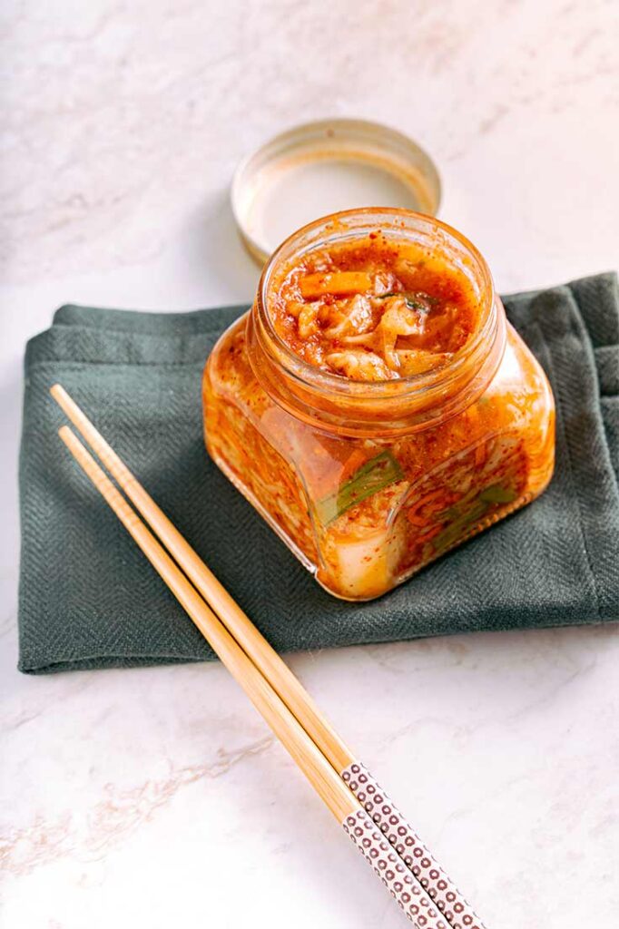 A side view of an open jar of kimchi.