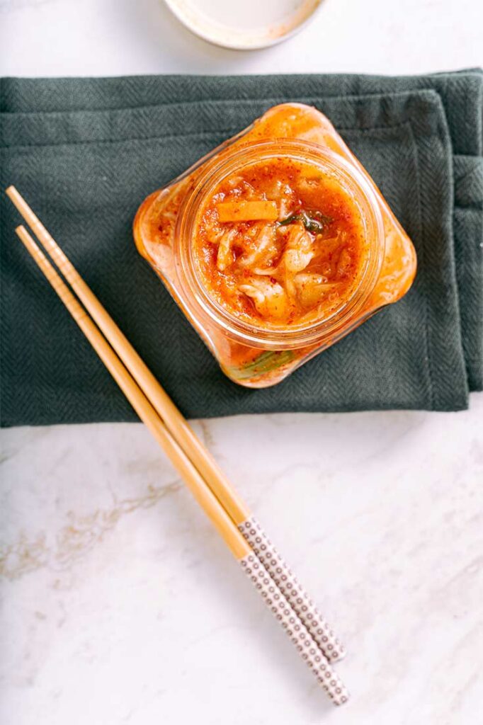 An overhead view of an open jar of kimchi.