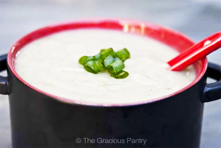 A black and red bowl filled with potato soup.