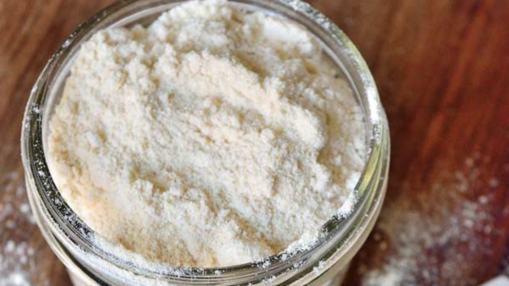 A glass jar with the lid off, filled with protein powder.